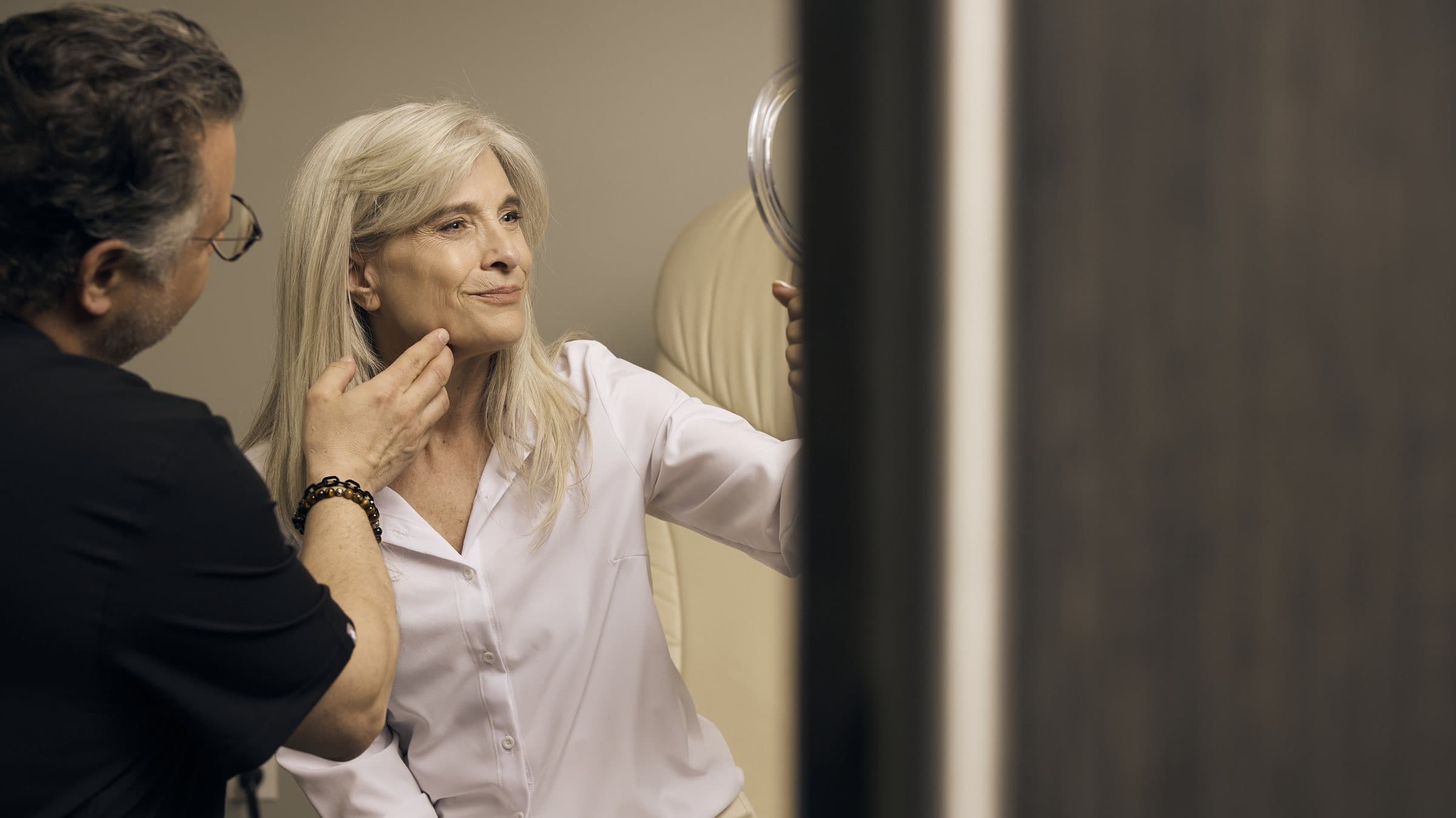 Dr. Heil with a patient at a consultation, checking her face in the mirror