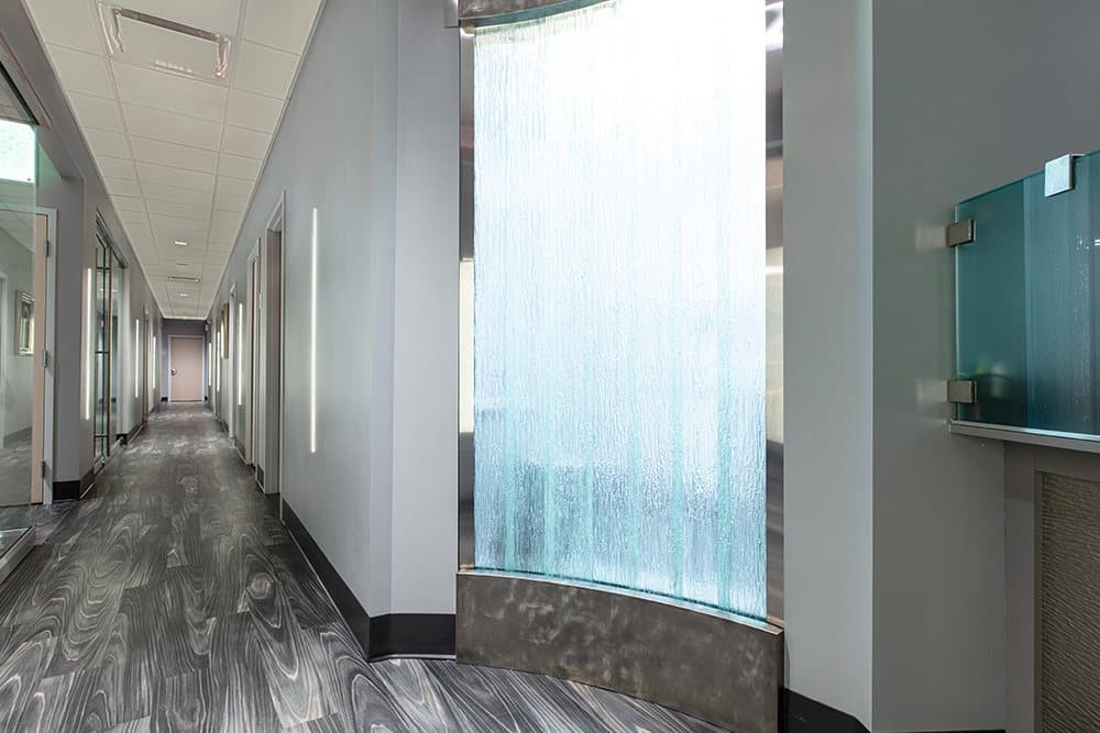 A backlit water wall running the length of a corridor