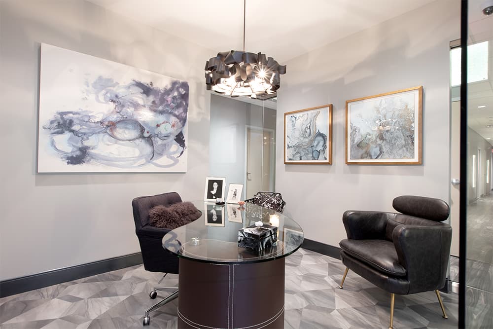A consultation room at Acqua Blu Medical Spa with leather chairs and abstract art