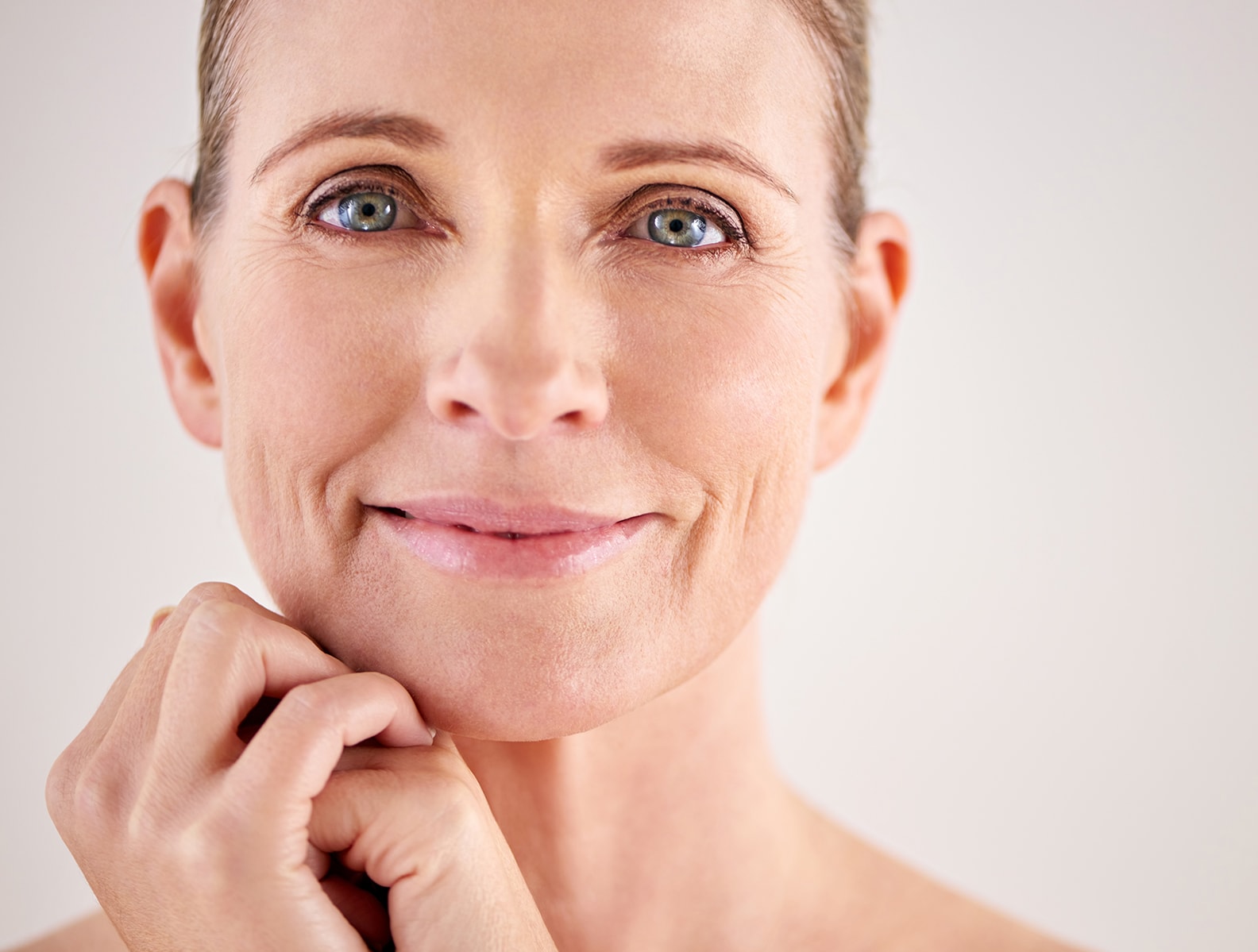 A woman with clear, even skin resting her chin on her hands