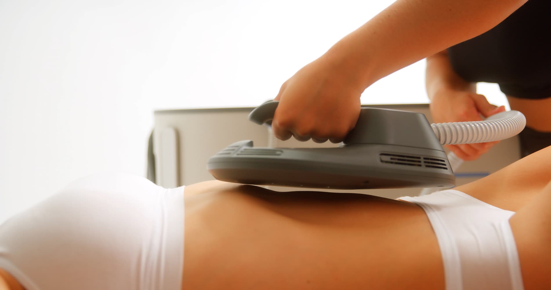 An Emsculpt NEO applicator strapped over a patient's abdomen