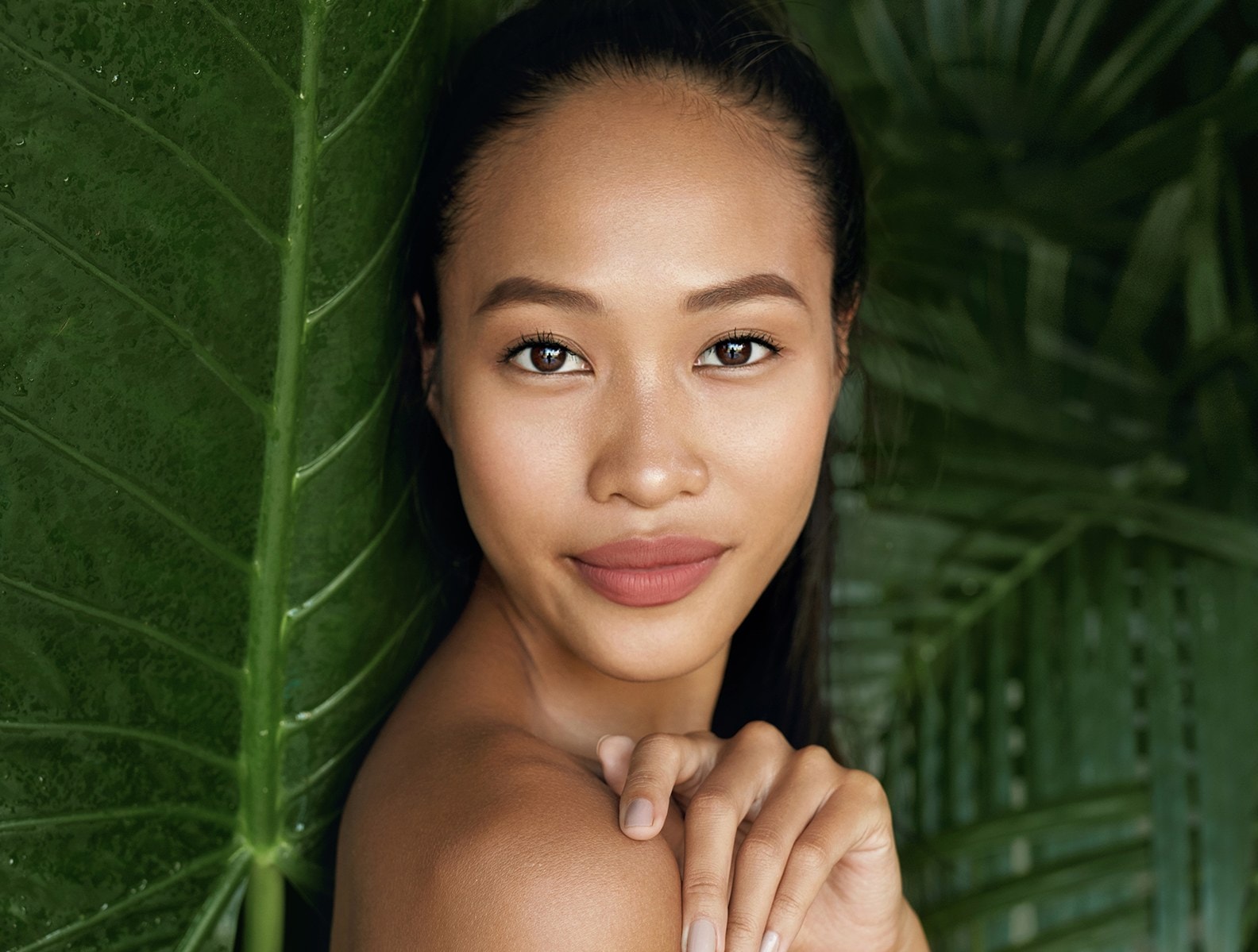 A woman in close portrait against dark green foliage